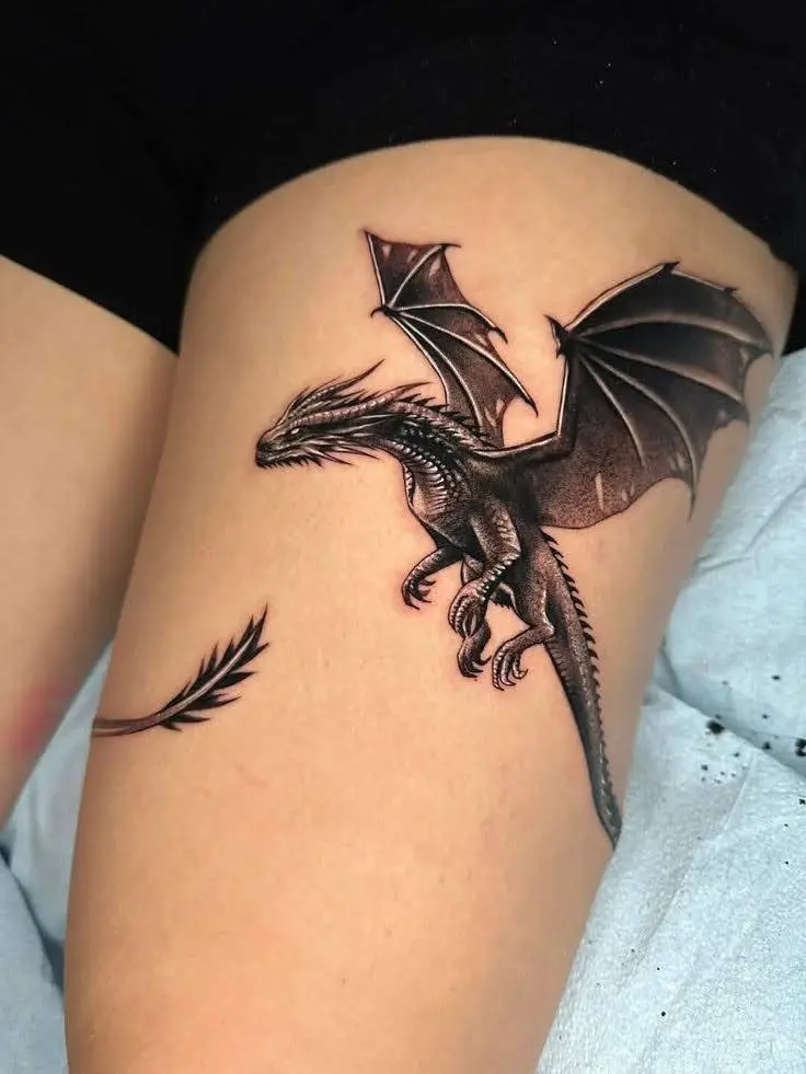 Dragon tattoo on a woman's thigh, wings spread.