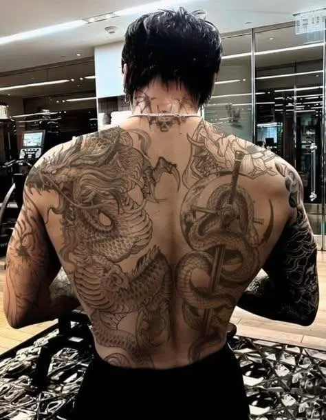 A full back tattoo with a dragon and a snake wrapped around a sword.