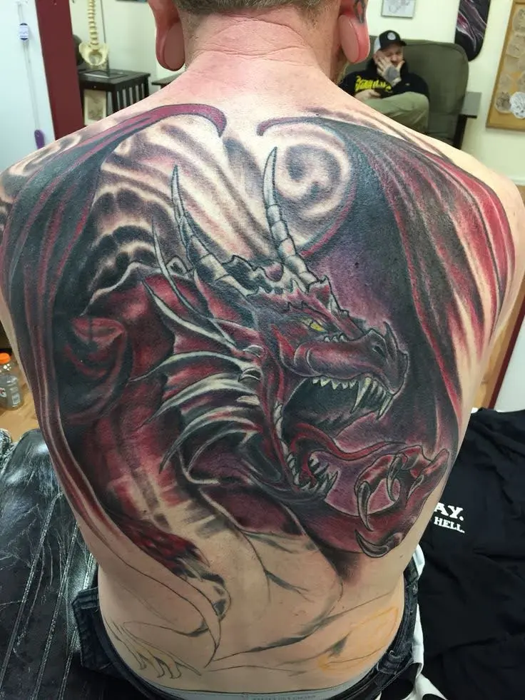 A vibrant red dragon tattoo with black wings and yellow eyes, covering a man's entire upper back.