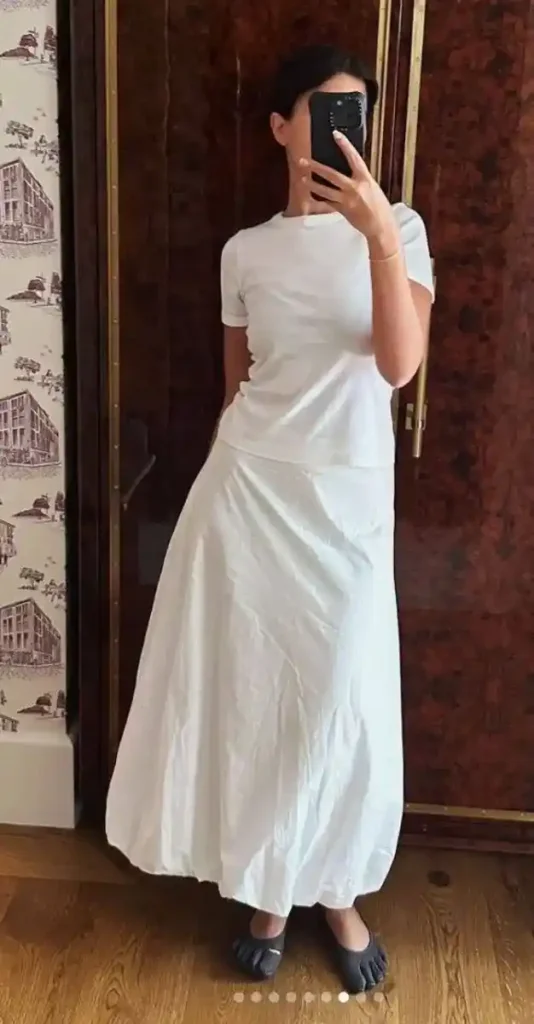 Casual chic look featuring a white top, flowy white skirt, and barefoot shoes, showcasing comfort and style.