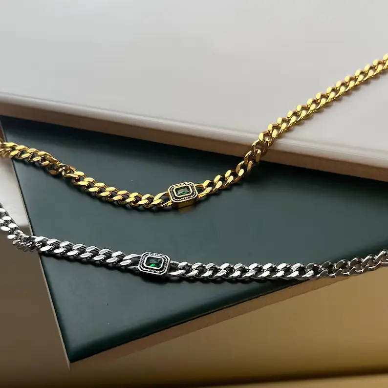 It shows 2 men's gold necklaces with gemstones in them.
