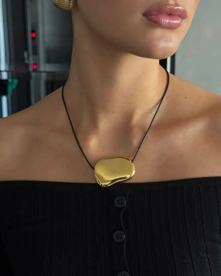 A woman wearing a trendy fall leather necklace with a gold stone.
