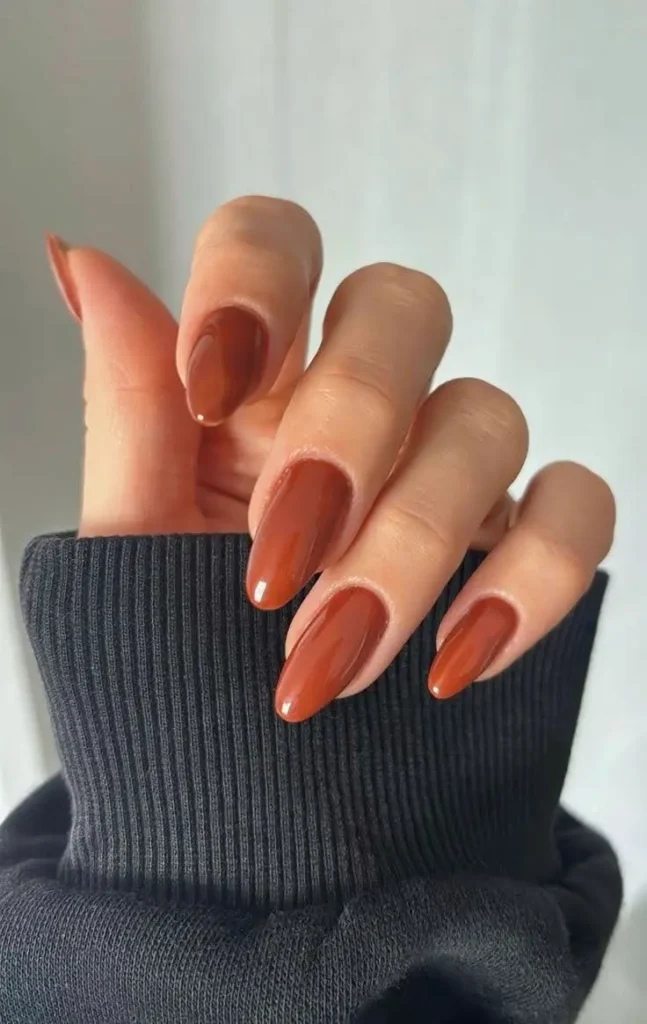 5 nails of a female hand displaying fall gingerbread nail art in brown color.