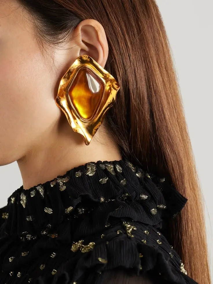 A female ear with moody, mystical gemstone earirngs.