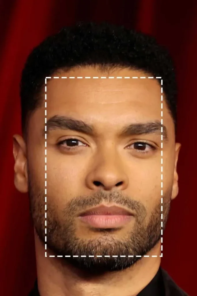 A close-up of Regé-Jean Page's face, with a white dashed rectangle highlighting his oblong/rectangular face shape.