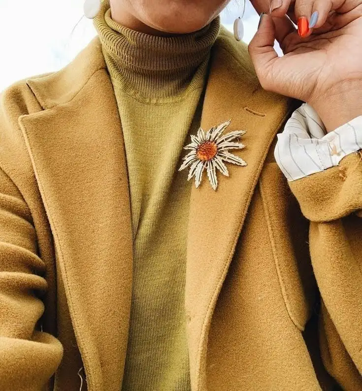 A woman wearing a playful brooch on her coat.