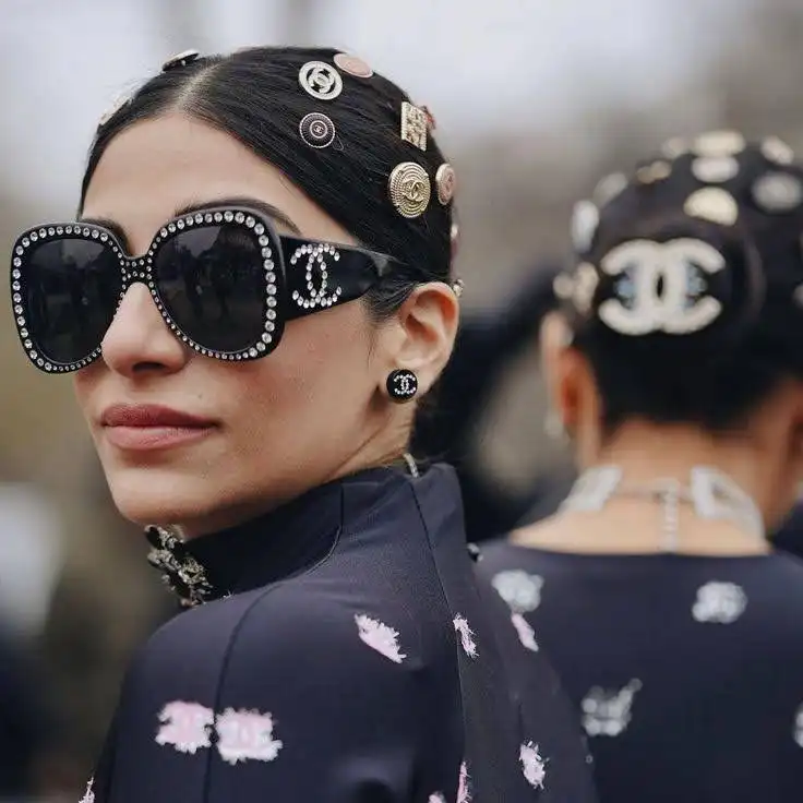 A stylish girl face wearing branded glasses and beads in her hair.