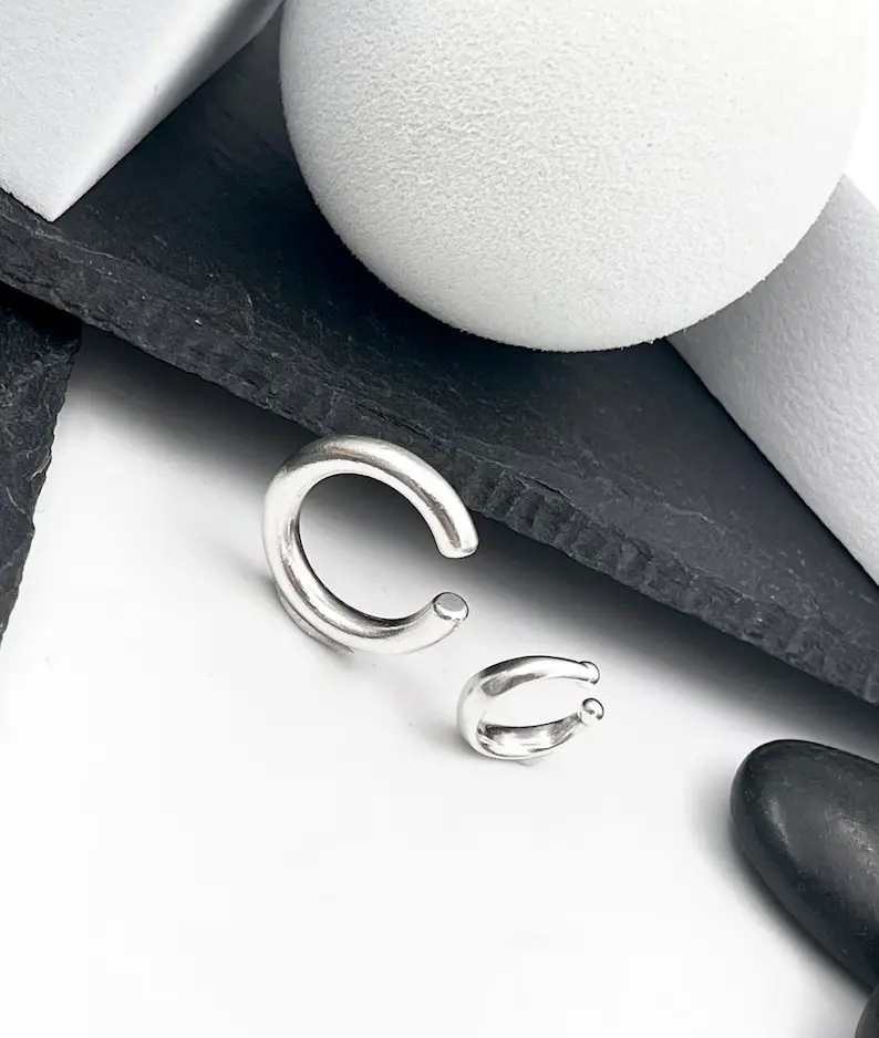 A man's ear cuff in a simple background lying on a flat surface. it can be worn without piercing.