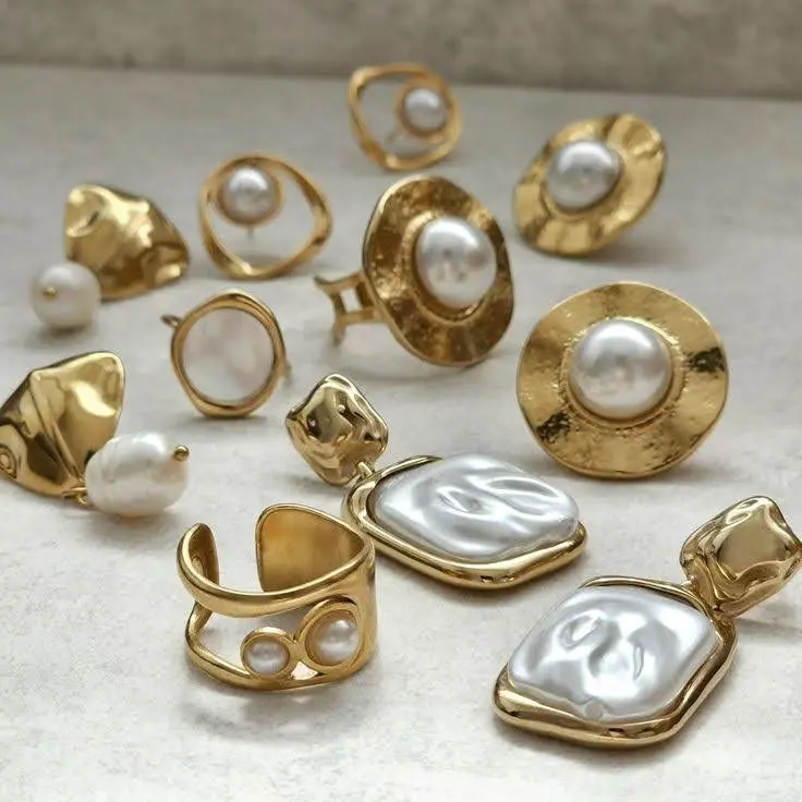 Different types of modern pearl jewelry rings and earrings on a flat surface.