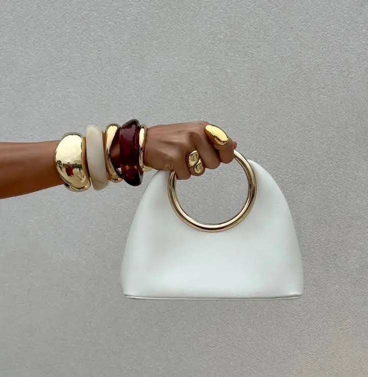 a hand with arm showing wearing autumn jewelry, bangles, and cuffs.