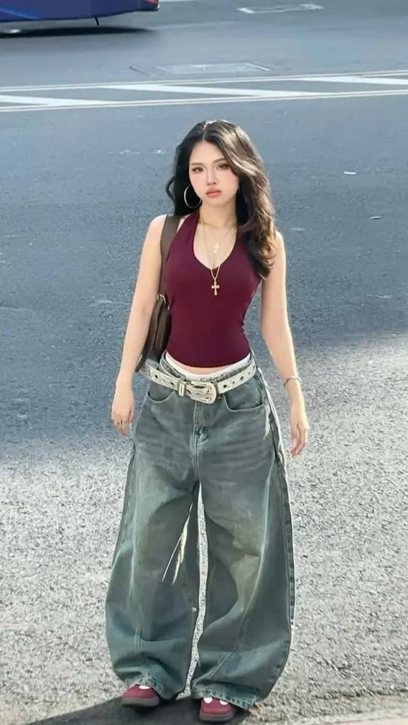 A woman in a Y2K-style outfit with a halter top and baggy, low-rise jeans.