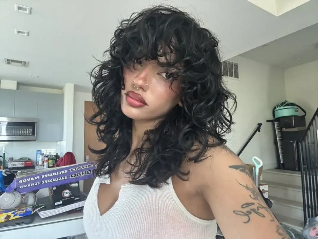 A girl with curly hair showing her wolf cut with curly bangs