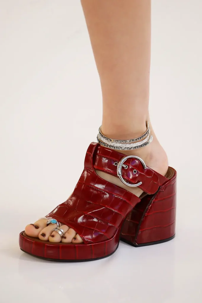 A girl foot with heel with gemstone rings on her foot fingure.