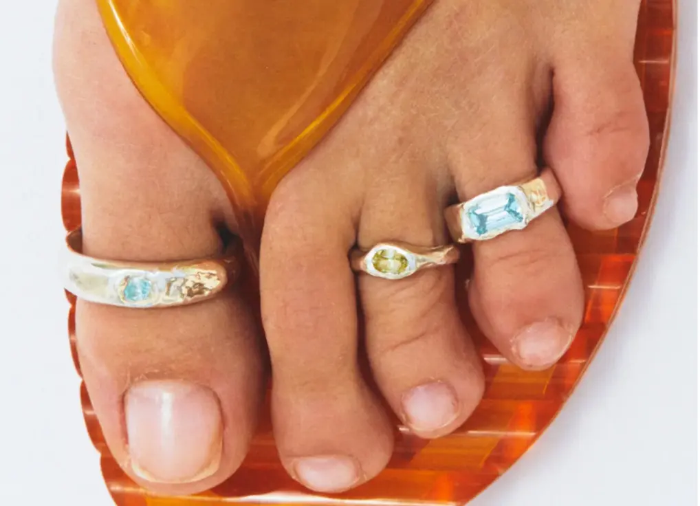 A girl's foot with 3 trending sterling silver toe rings.
