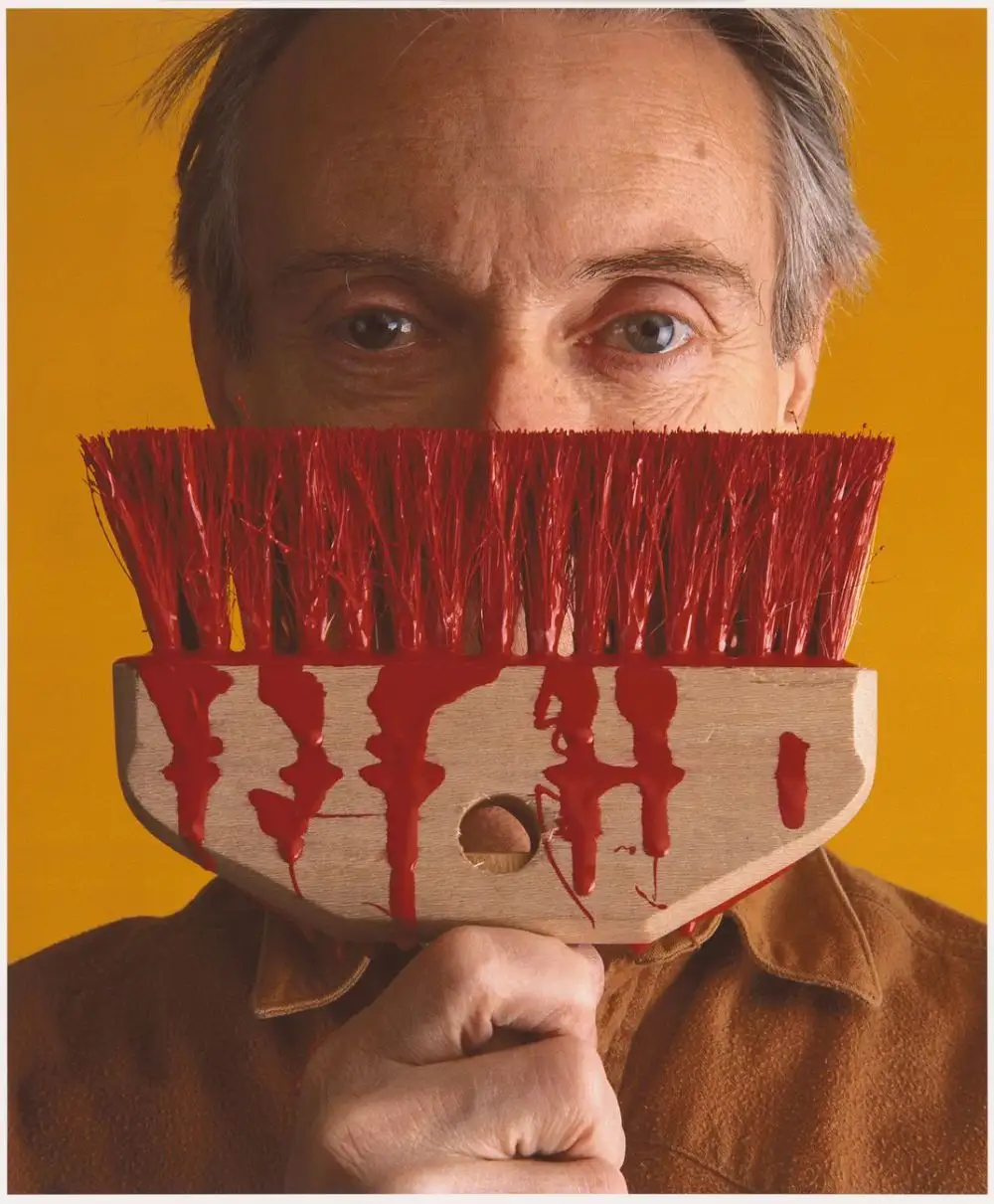 Roy Lichtenstein with holding a brush with red color paint on it infront of face