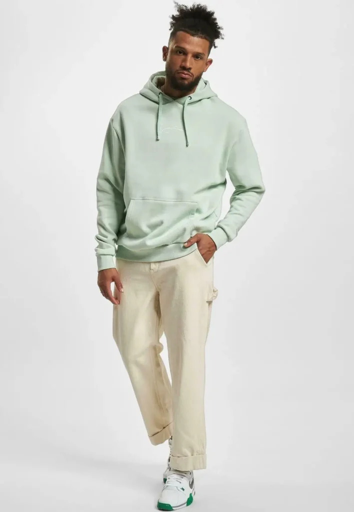 a boy in a sage green hoodie and white trouser and sneaker