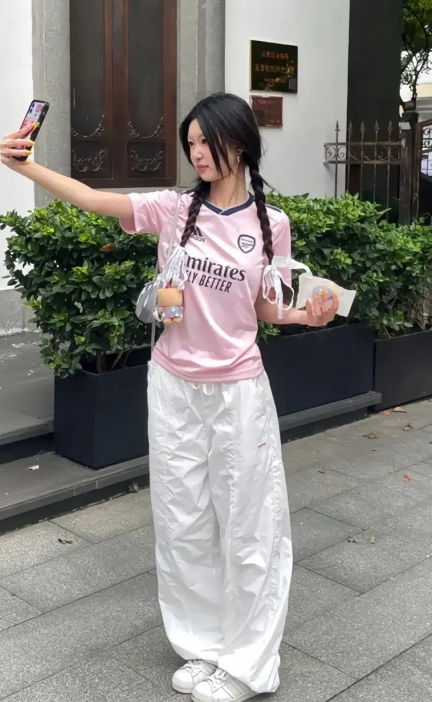 a girl in pink tee shirt and white wide leg pant taking selfie