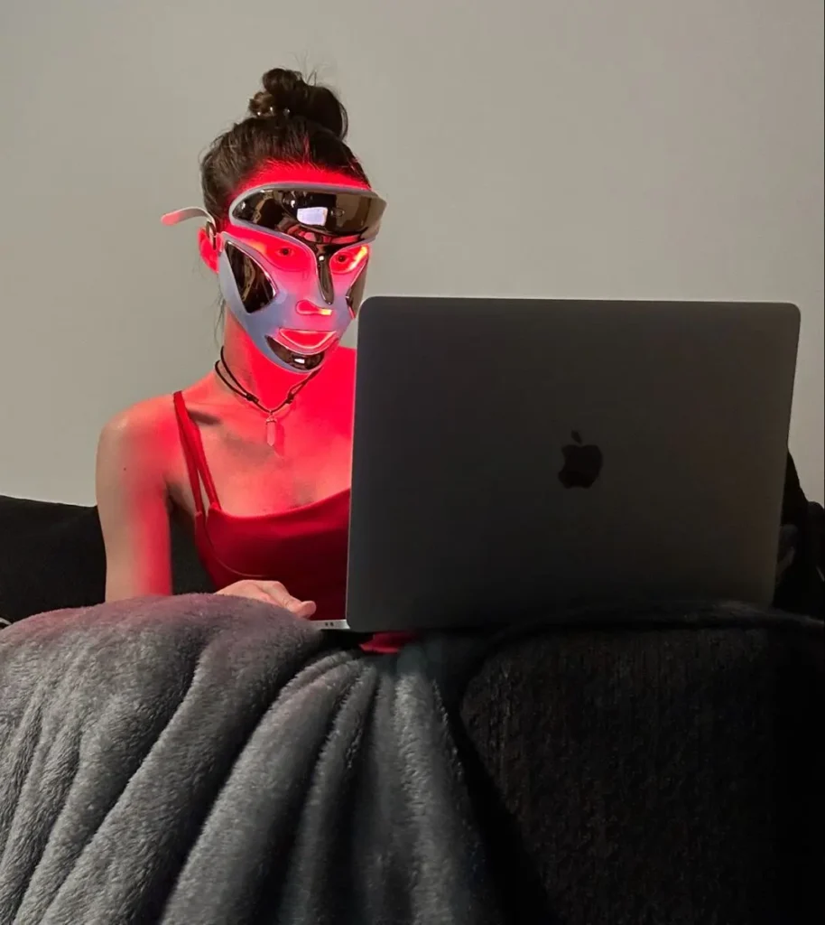 a woman in a red light therapy mask wearing on face