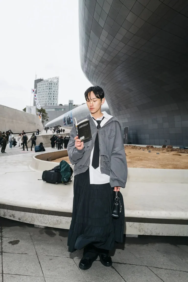 a man standing with a book in hand in Seoul street fashion