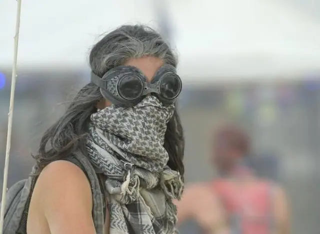a girl in a burning man desert dust storm with covered face